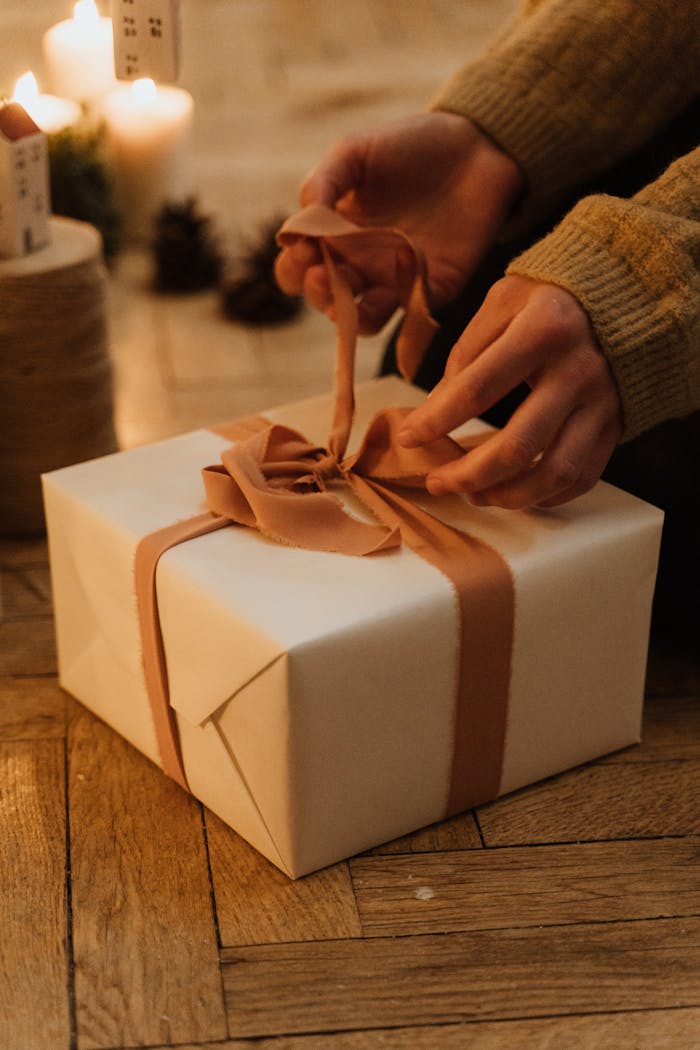 gallery-3 Hands carefully unwrap a gift box with a ribbon in a warm, cozy indoor setting.